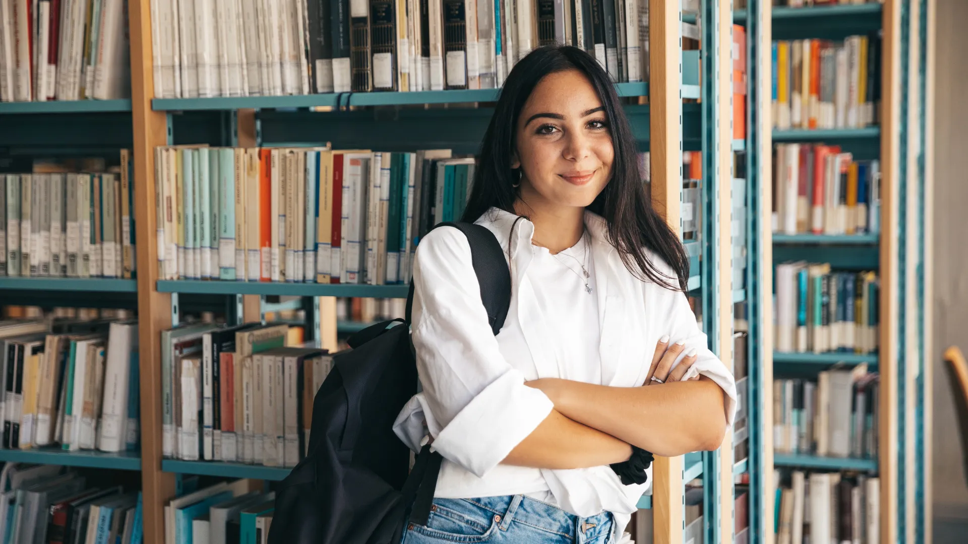 Confident university student standing in a library, representing academic growth through educational travel experiences.