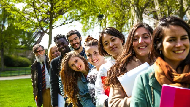 Group of students standing together outdoors in a line, smiling during a student tour experience.