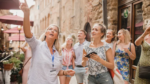Group of travelers exploring a historic city street with a tour guide, enjoying a cultural travel experience.